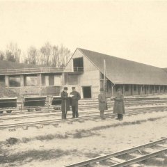 Lagerhalle mit Personen und Schienen im Vordergrund